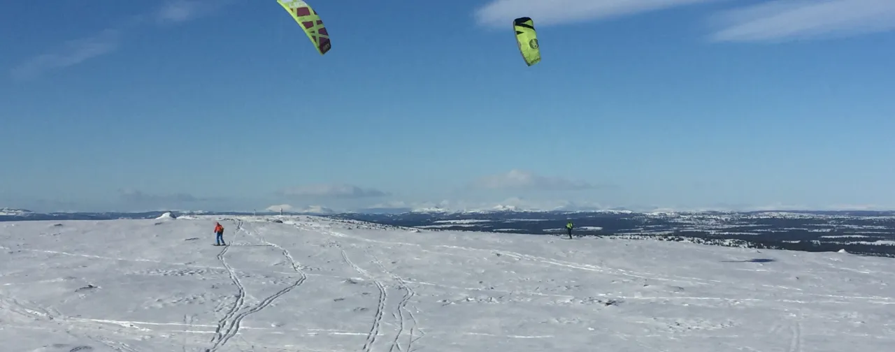 En gruppe mennesker som kiter i snøen