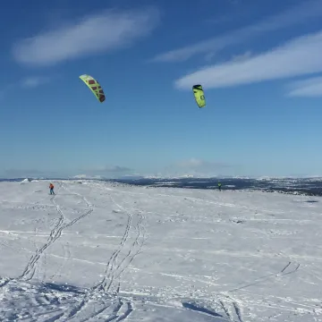 En gruppe mennesker som kiter i snøen