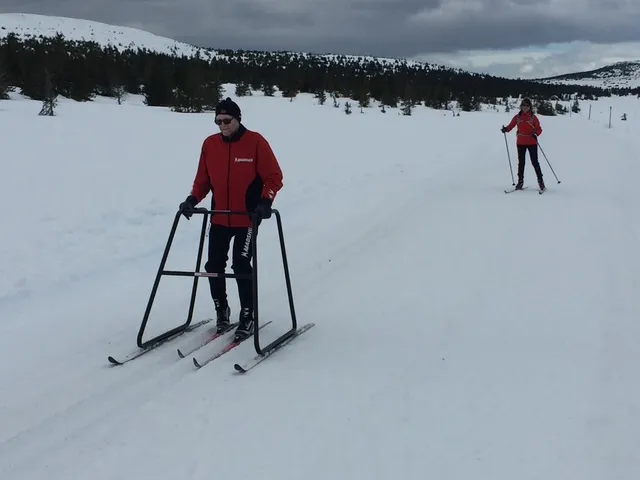 Mann i rød skijakke på ski med skilator